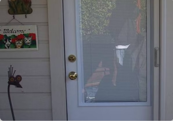 A person reaching for a door handle through a glass door, with a 