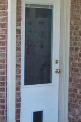 White door with screen, brick wall, and a small pet door.