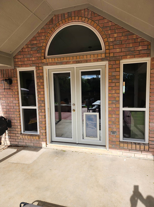 Brick exterior with French doors, sidelights, and arched window. Dog door in the center.