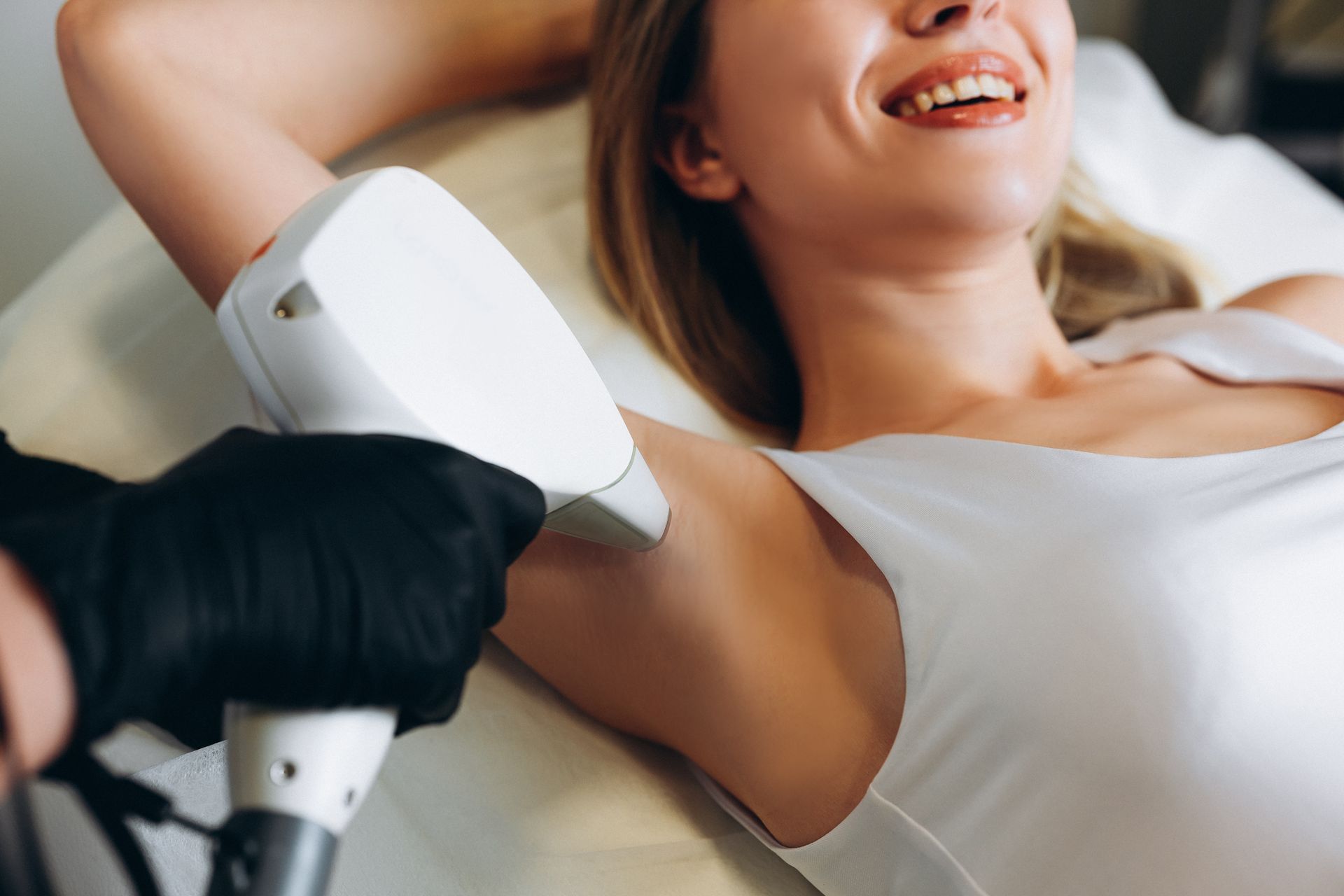 A woman is getting a laser hair removal treatment on her armpit.