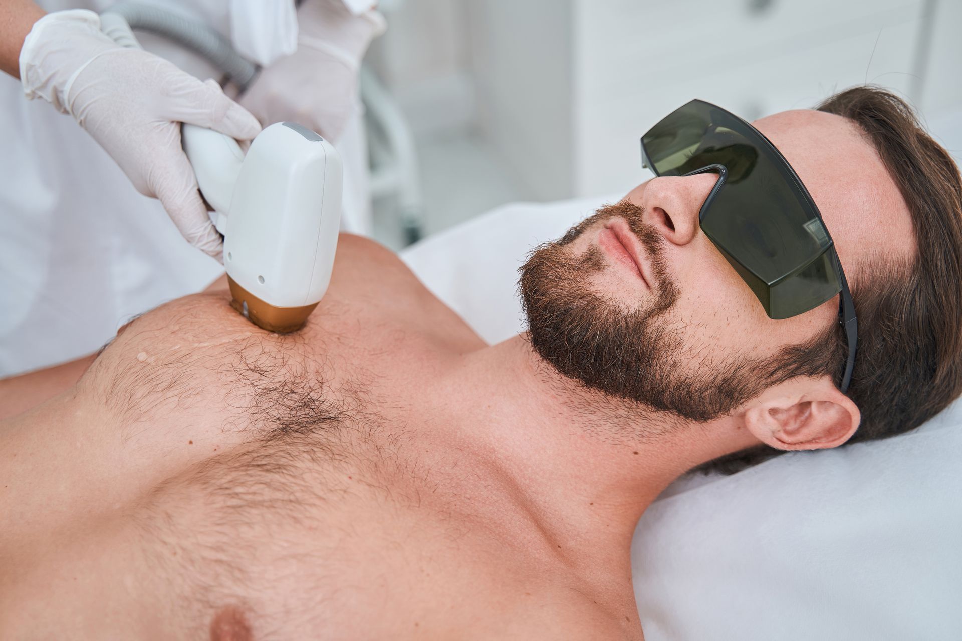 A man is getting a laser hair removal treatment on his chest.