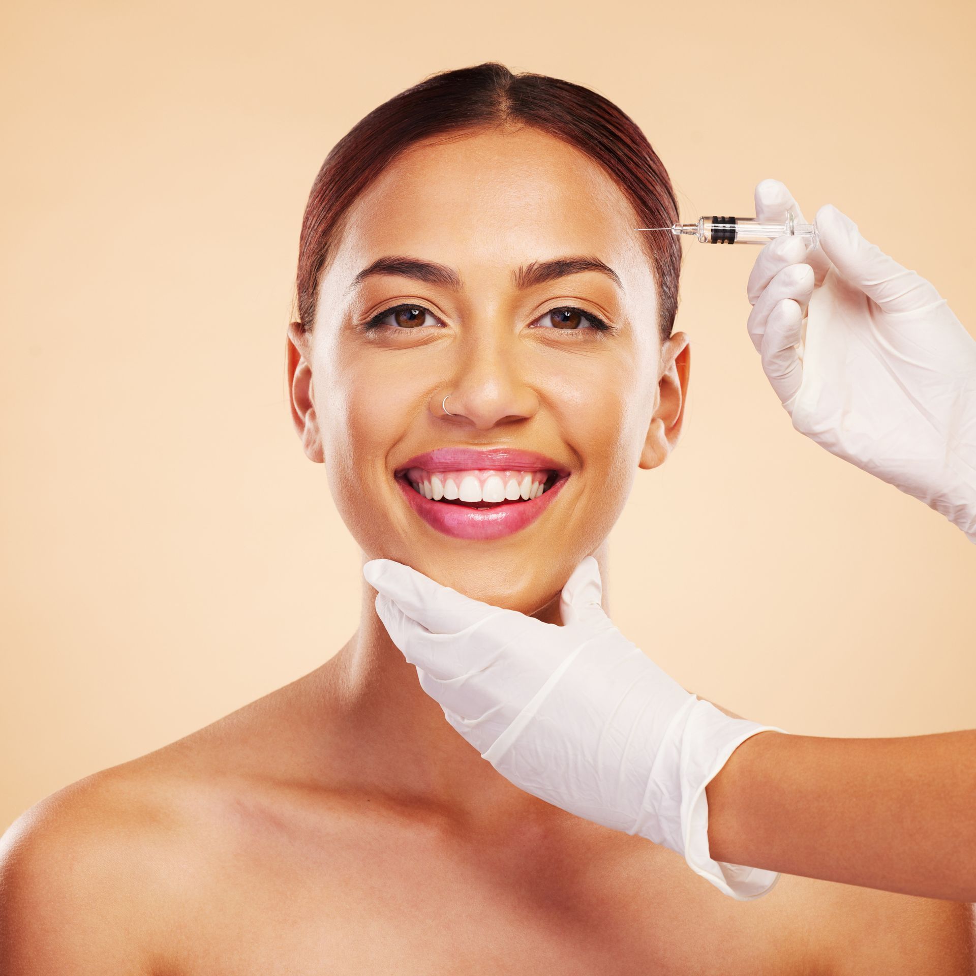 A woman is smiling while getting a botox injection in her face.