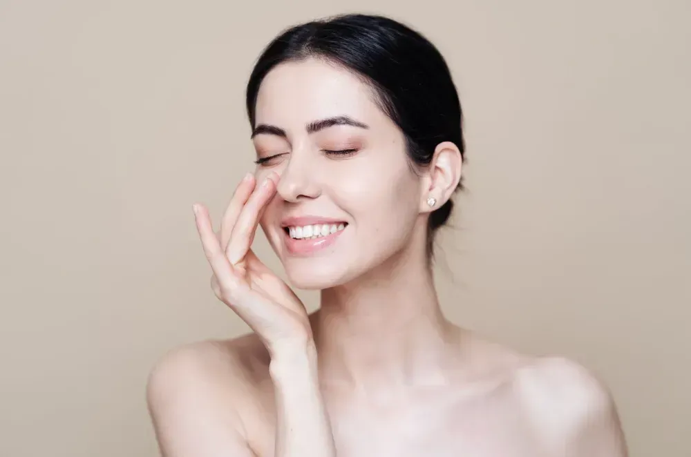 a woman is touching her face with her hand and smiling .