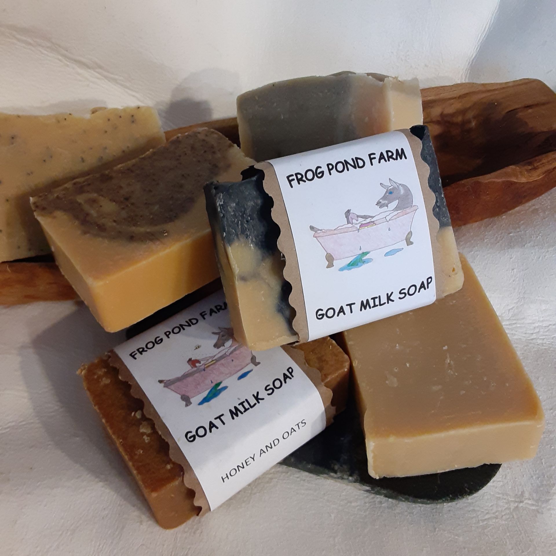 A frog pond farm goat milk soap is surrounded by other soaps