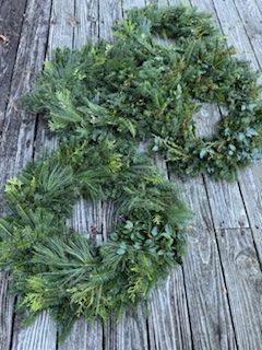 Two wreaths are sitting on a wooden deck.