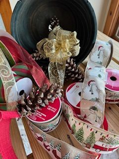 A bunch of christmas ribbons and pine cones are sitting on a wooden table.