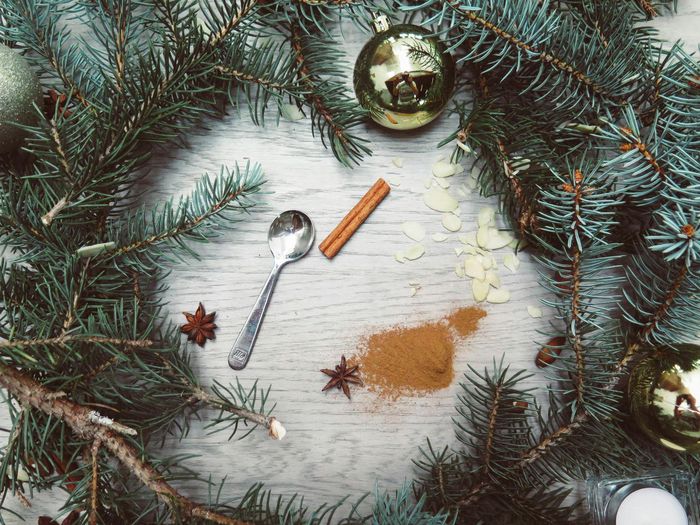 A spoon , cinnamon sticks , star anise and christmas decorations on a wooden table.