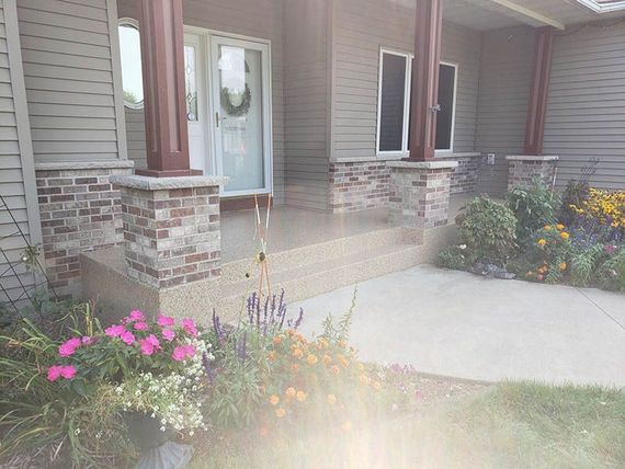 A house with a porch and flowers in front of it.