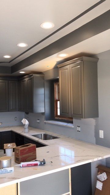 A kitchen with gray cabinets and white counter tops