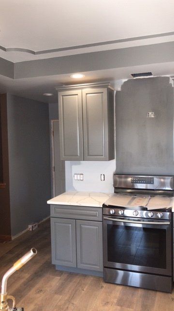 A kitchen with stainless steel appliances and gray cabinets