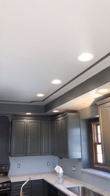 A kitchen with gray cabinets and a stainless steel sink