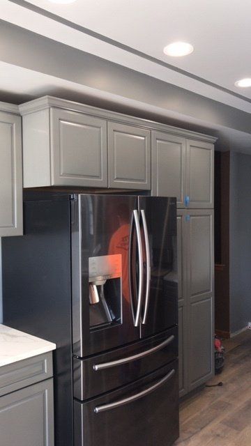 A kitchen with gray cabinets and a black refrigerator
