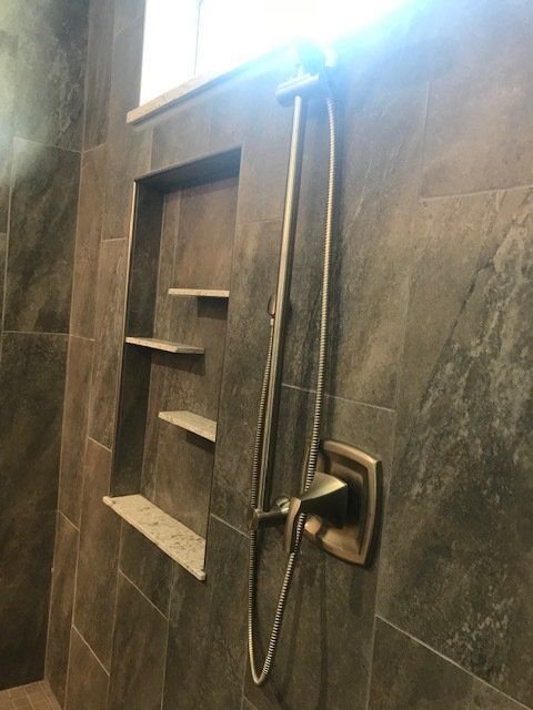 A shower with a shower head and shelves on the wall