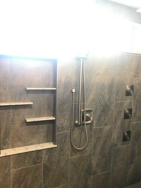 A bathroom with a shower , shelves , and a window.