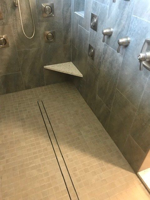 A bathroom with a walk in shower and a corner shelf.