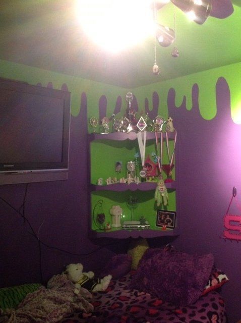 A bedroom with purple walls and green shelves.