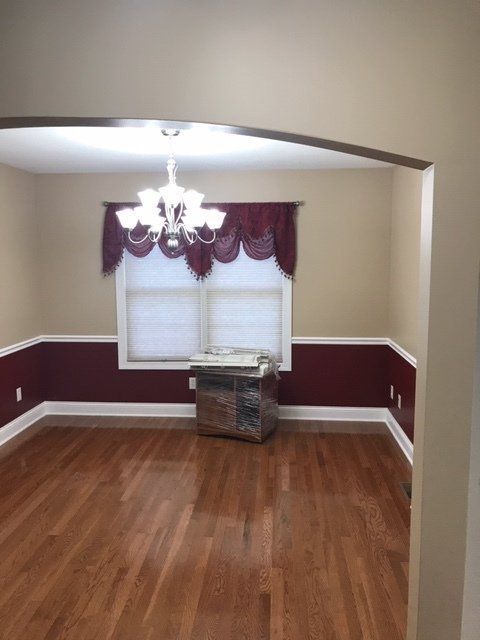 An empty dining room with hardwood floors and a chandelier
