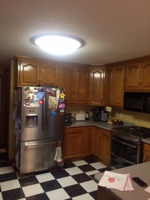 A kitchen with wood cabinets and a stainless steel refrigerator