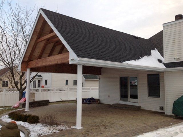 A white house with a black roof and a white fence