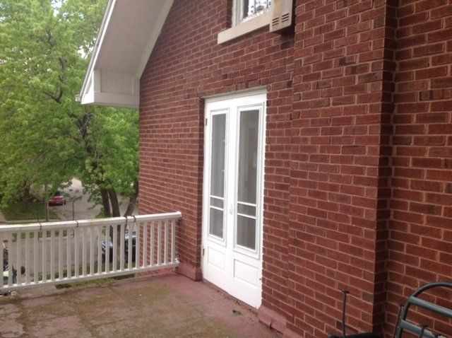 A brick building with a balcony and a white railing.