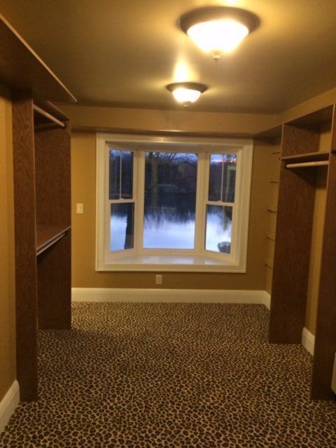 A walk in closet with a window and leopard print carpet