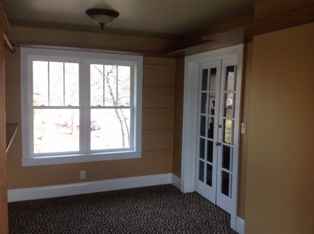 An empty room with a large window and french doors