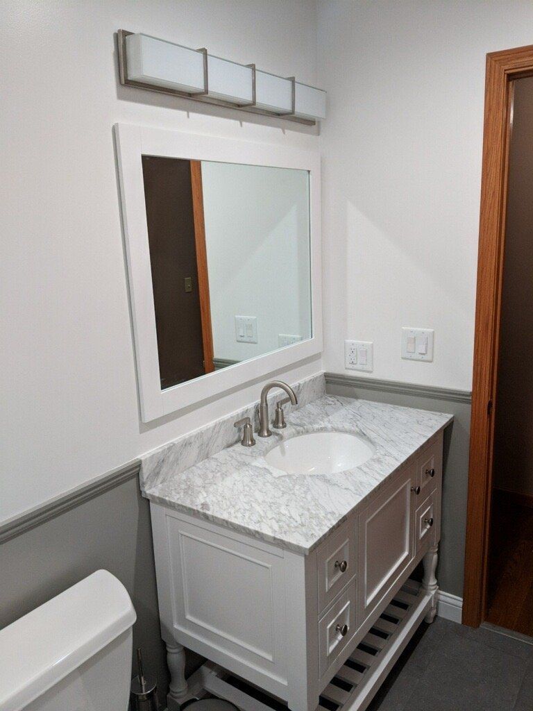 A bathroom with a sink , toilet and mirror.