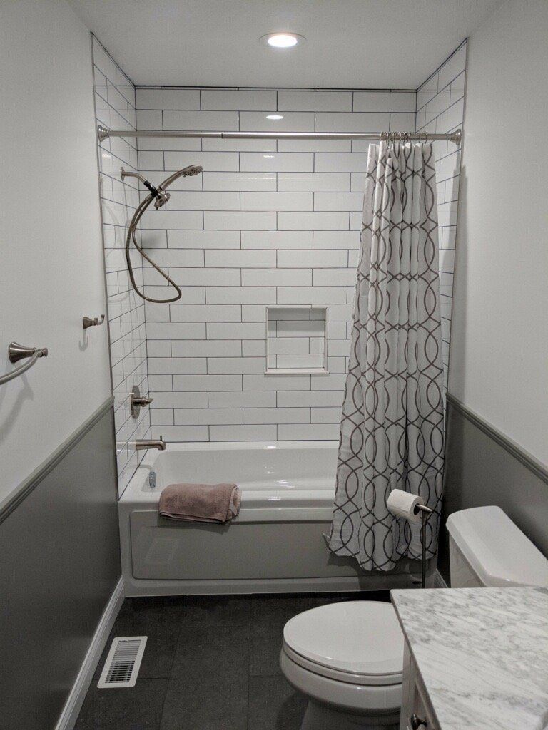 A bathroom with a tub , toilet , and shower.