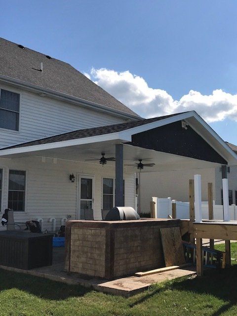 A white house with a covered porch and a grill
