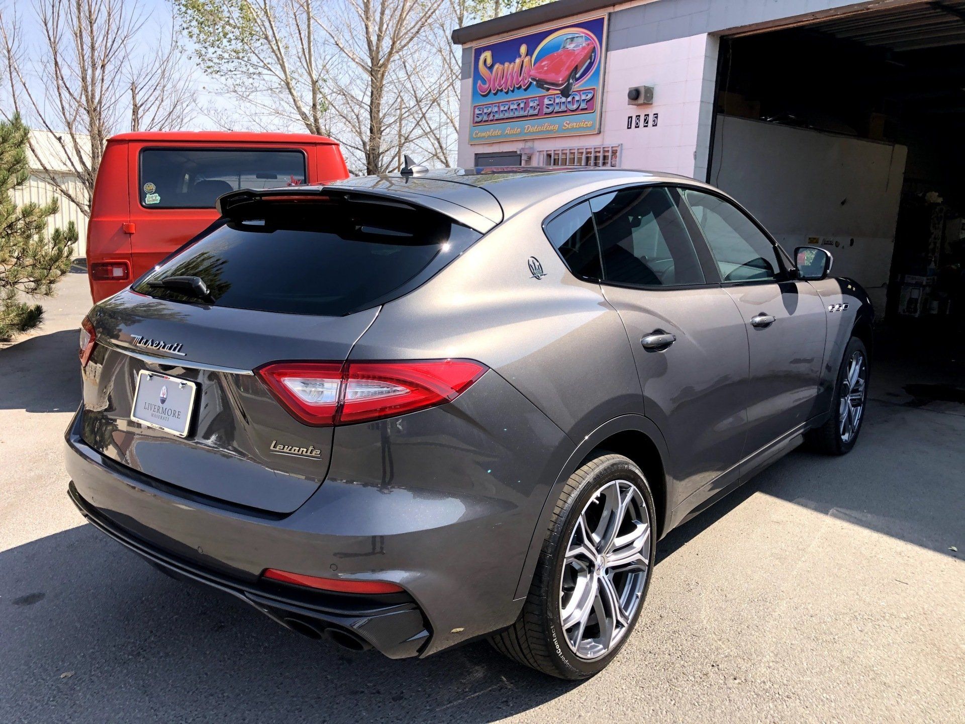 A gray car is parked in front of a garage.