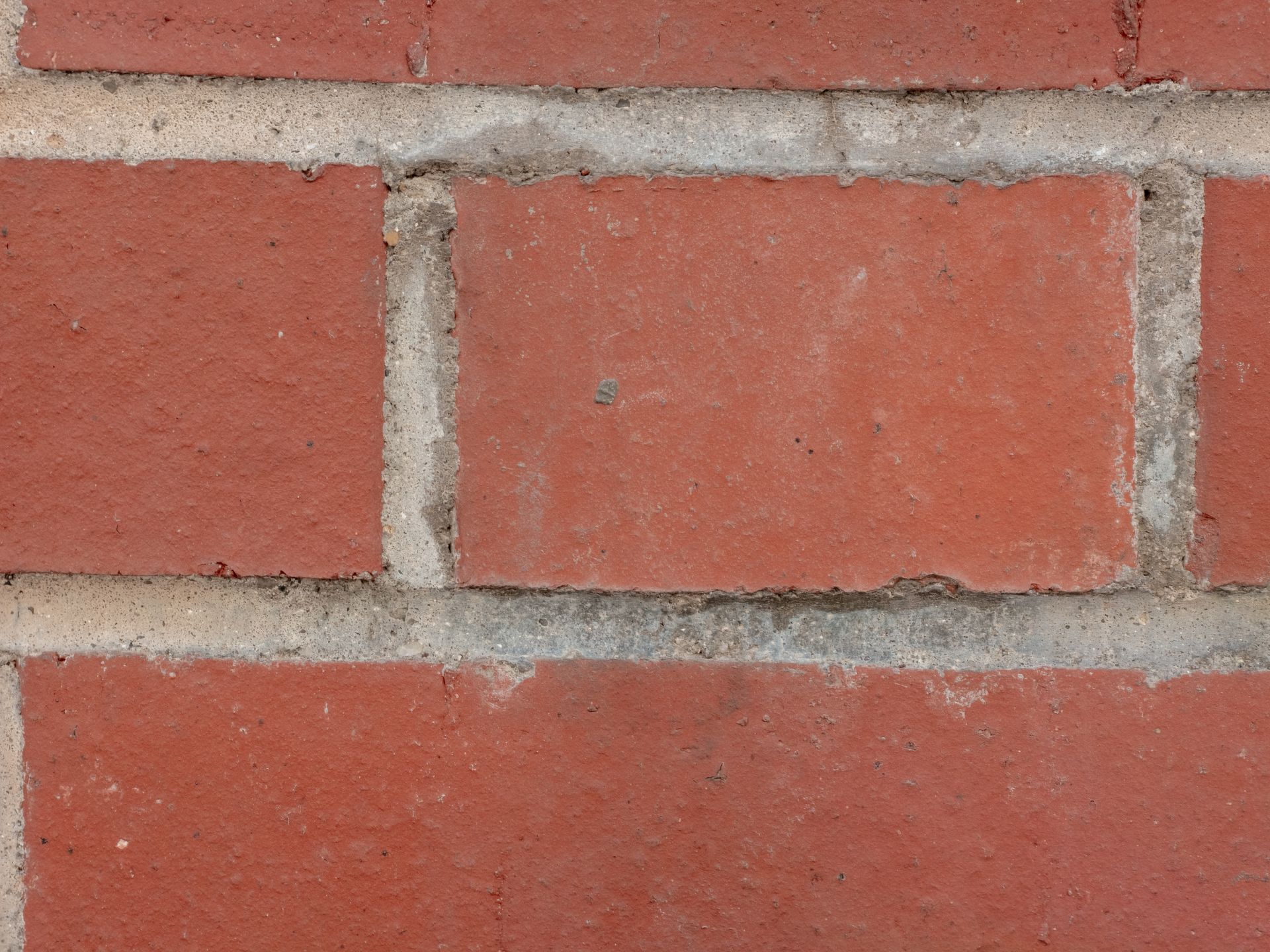 Mur de briques rouges avec mortier gris clair.