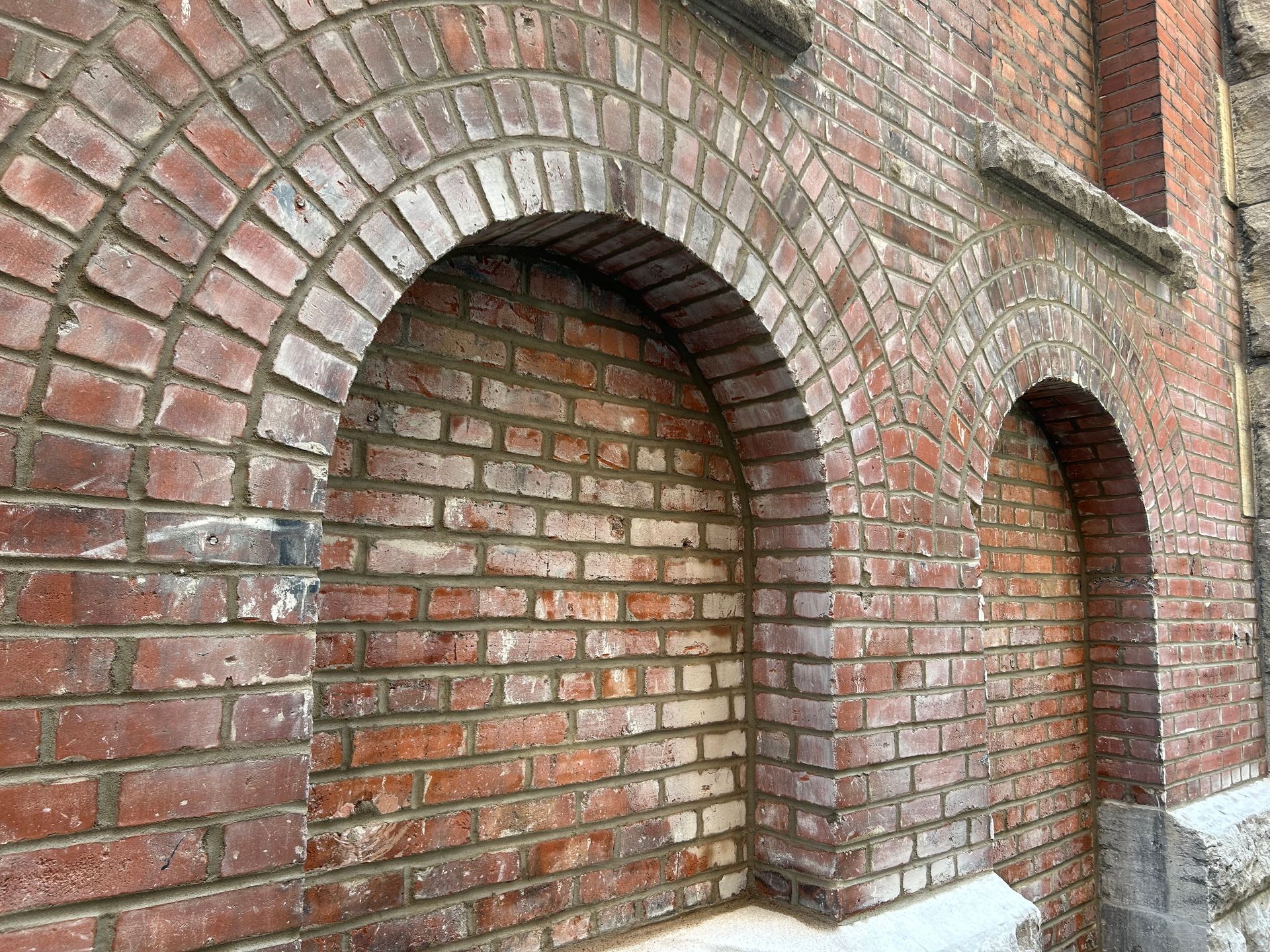 Arches en briques sur un mur de briques rouges patiné.