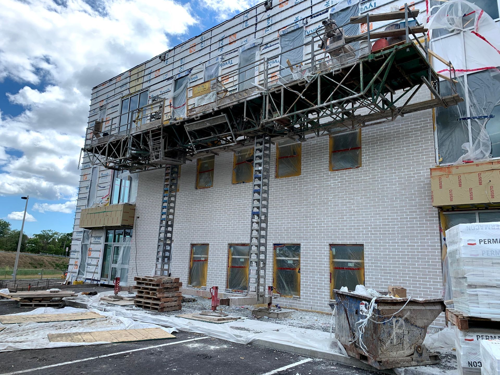 Bâtiment en construction avec échafaudage et plateforme de travail fixés sur le côté.