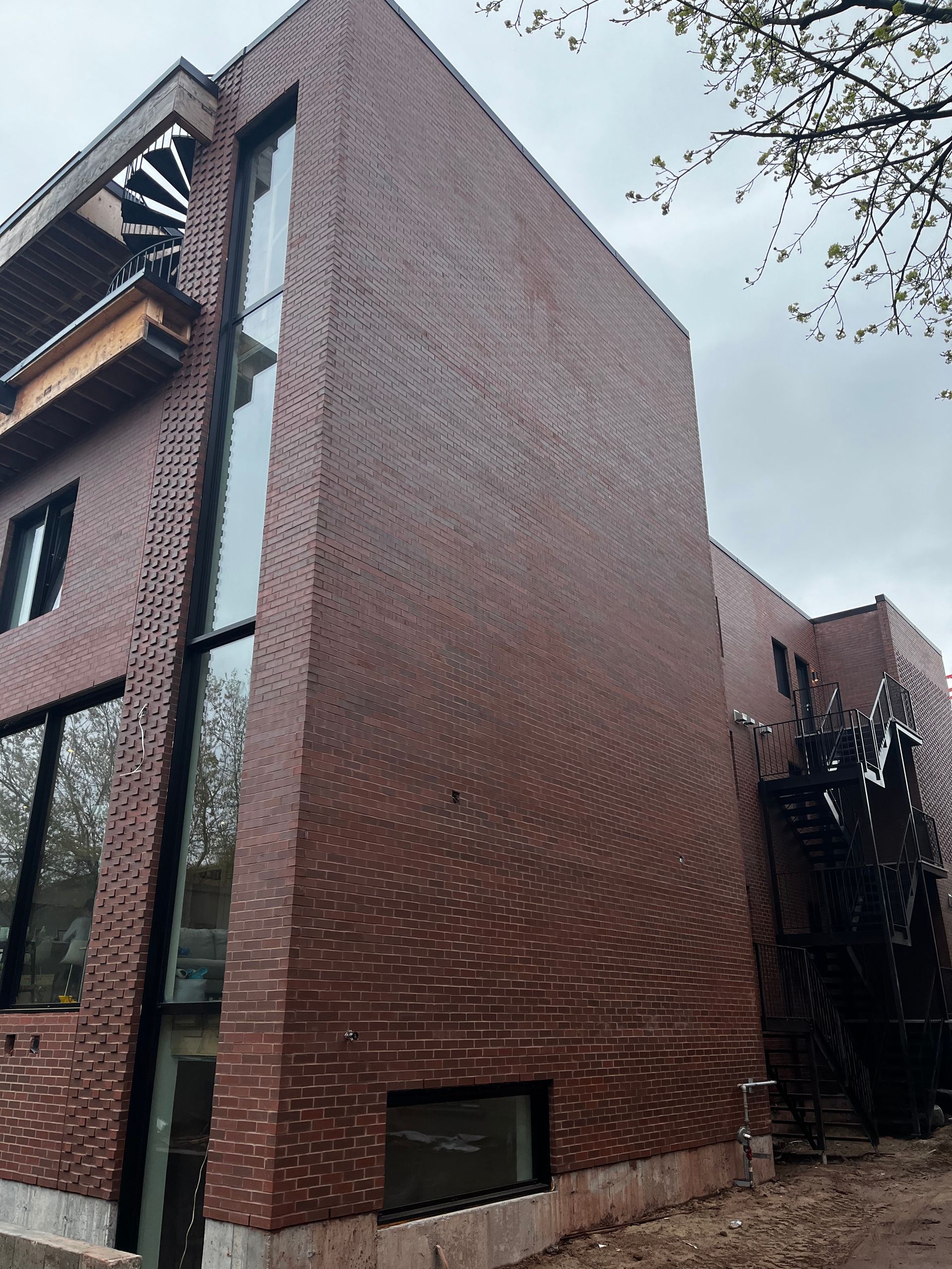 Bâtiment en briques avec de hautes fenêtres, un escalier latéral et un balcon avec un escalier en colimaçon.
