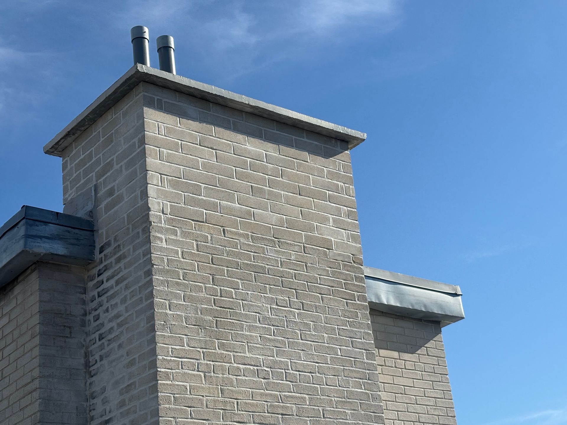 Cheminée en pierre avec feu allumé, installée sur un mur à deux étages. Échafaudage sur le côté.