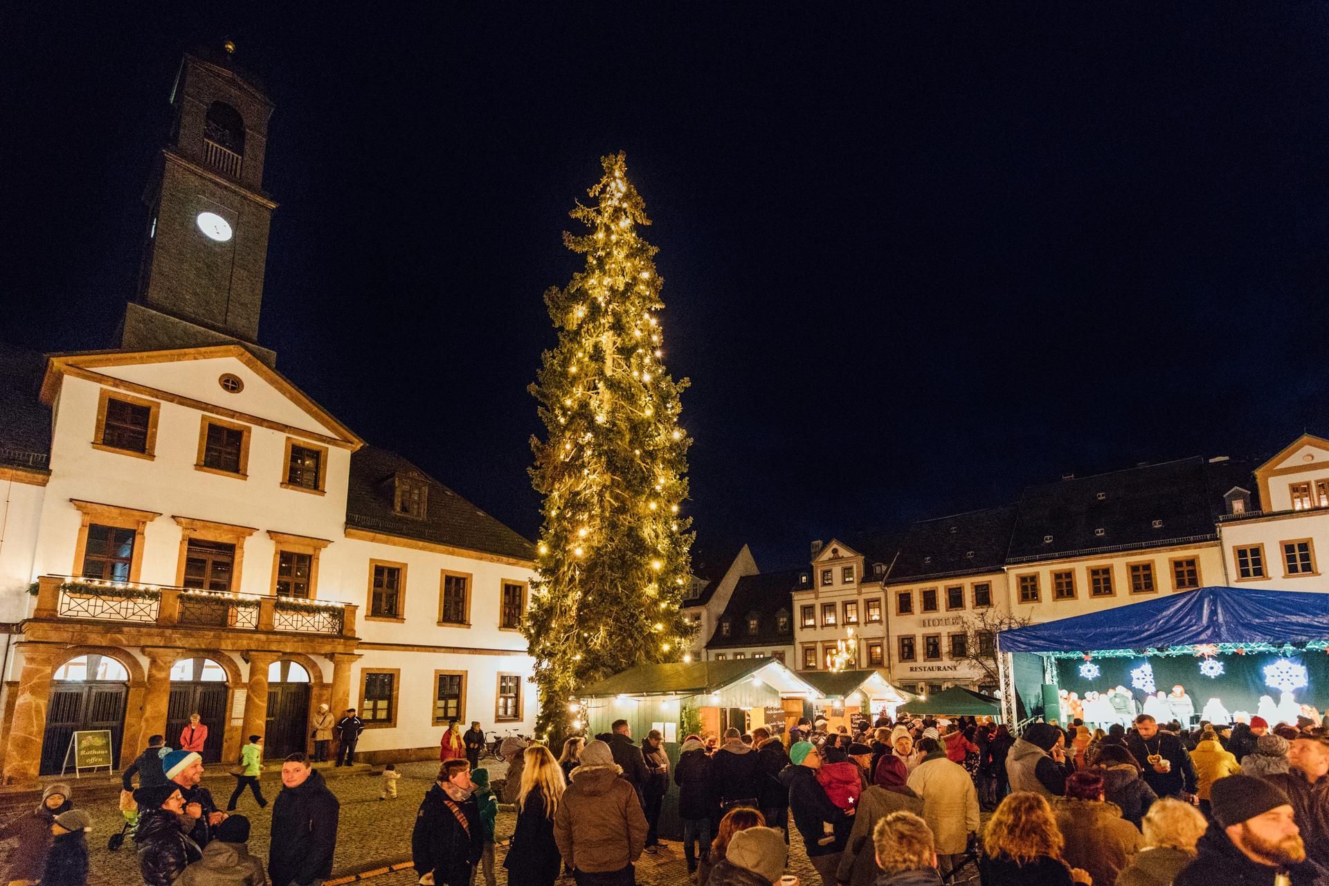Blick auf den Weihnachtsmarkt Rochlitz mit Verkaufsständen und beleuchtetem Weihnachtsbaum