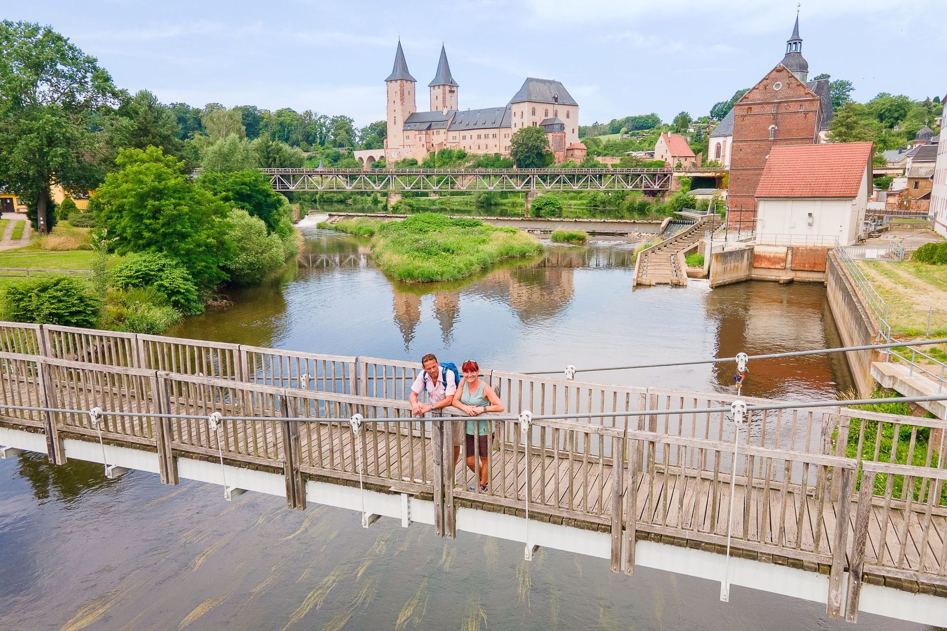 Wanderer auf der Hängebrücke bei Zaßnitz, im Hintergrund thront Schloss Rochlitz