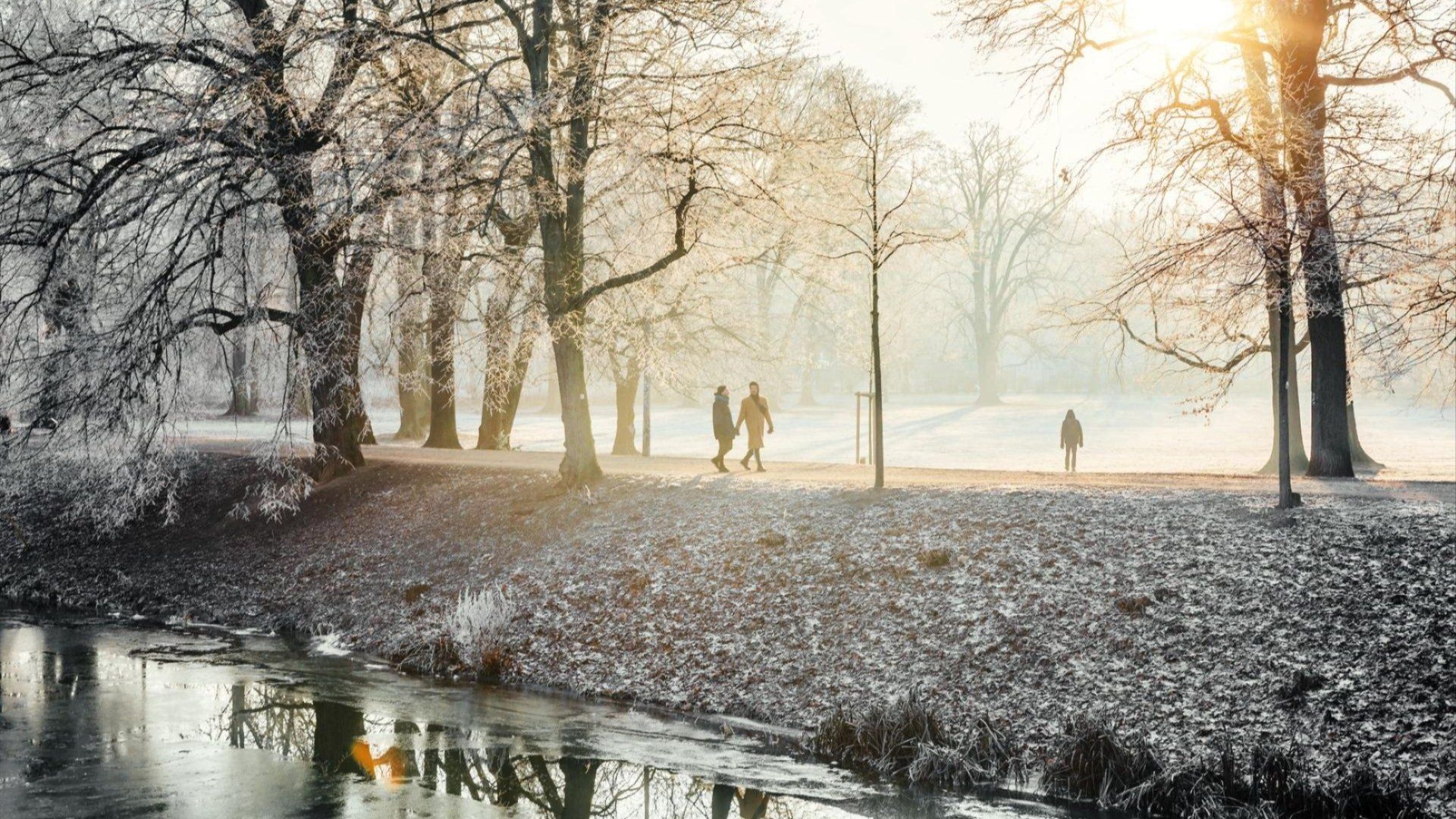 Spaziergänger in winterlicher Landschaft am Fluss