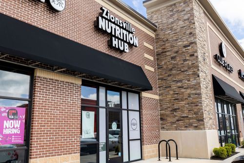 A brick building with a sign that says `` zionsville nutrition hub '' on it.