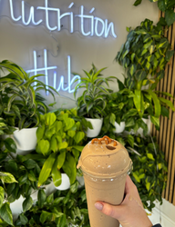 A person is holding a smoothie in front of a sign that says nutrition hub