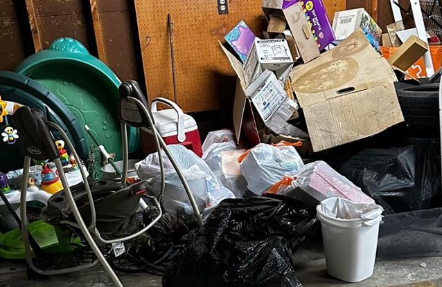 A pile of garbage in a garage including a rocking chair.