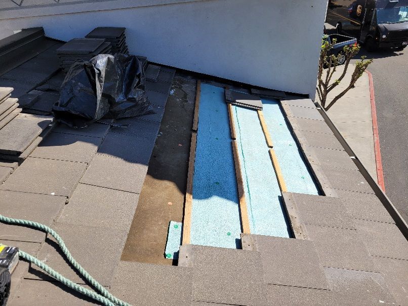A pale blue house with a dark roof, shutters, and a small window in the upper center.