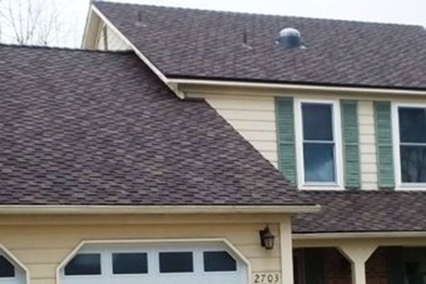 House with brown shingles, beige siding, and green shutters.