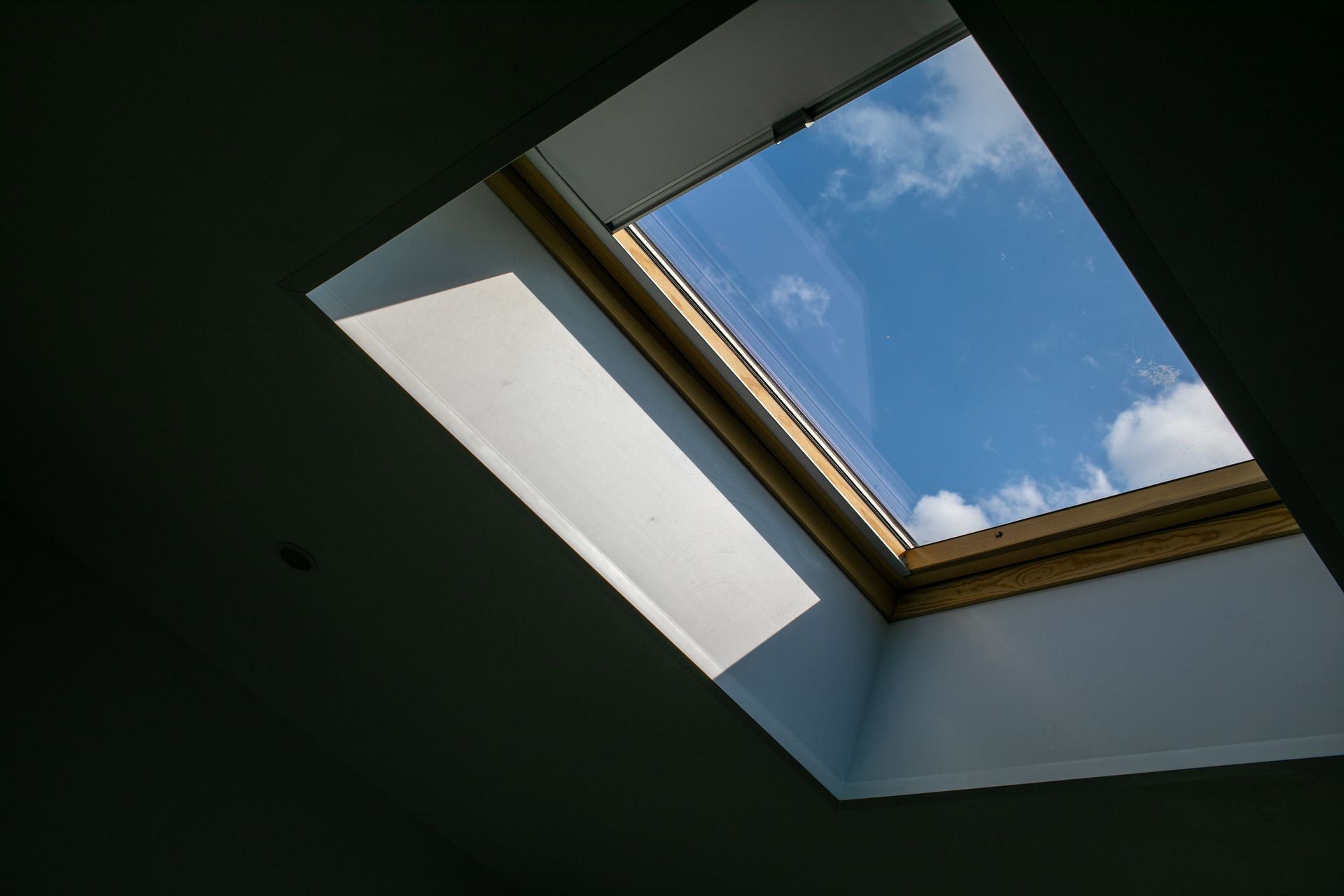 Skylight framed in white, showing a blue sky with clouds.