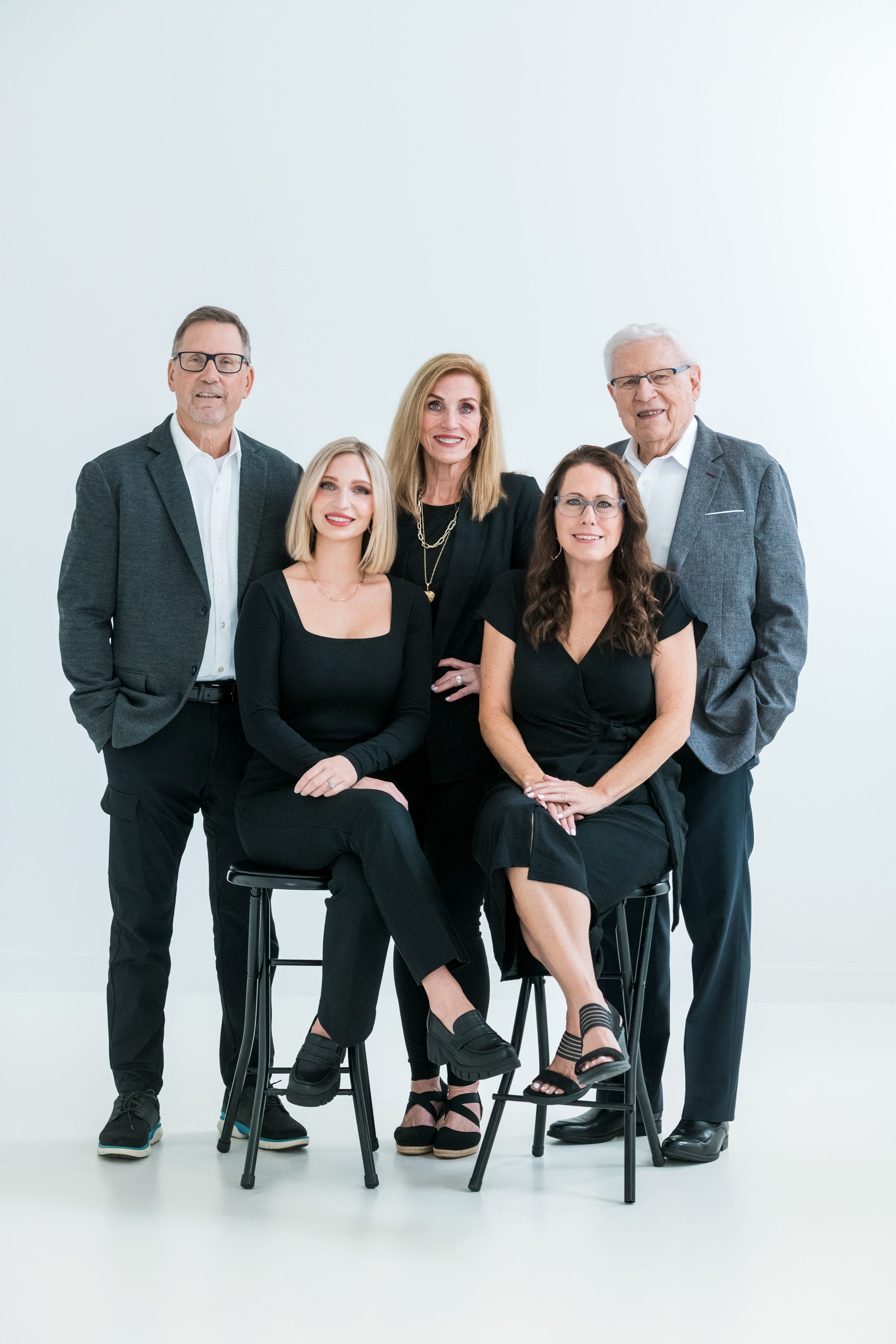 An elderly couple is holding a baby and a toddler.