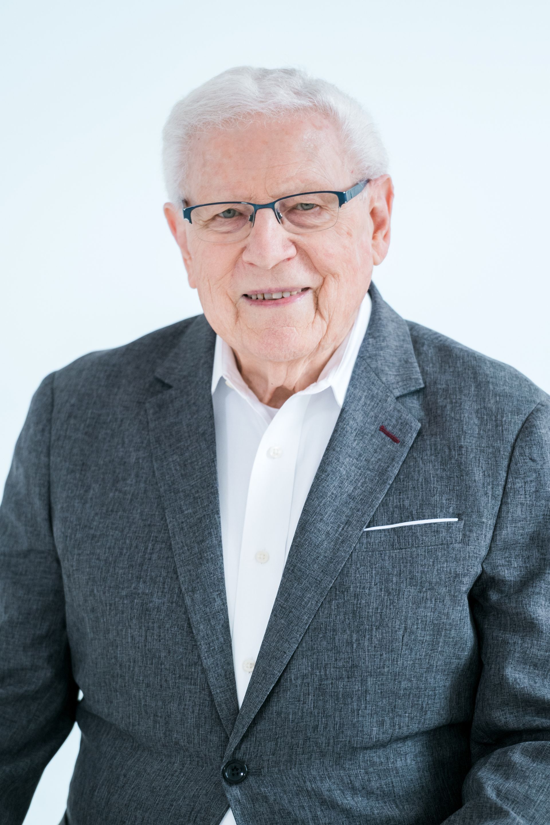 A man wearing a purple shirt and tie is smiling for the camera.