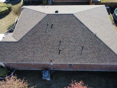 An aerial view of a brick house with a roof that has shingles on it.