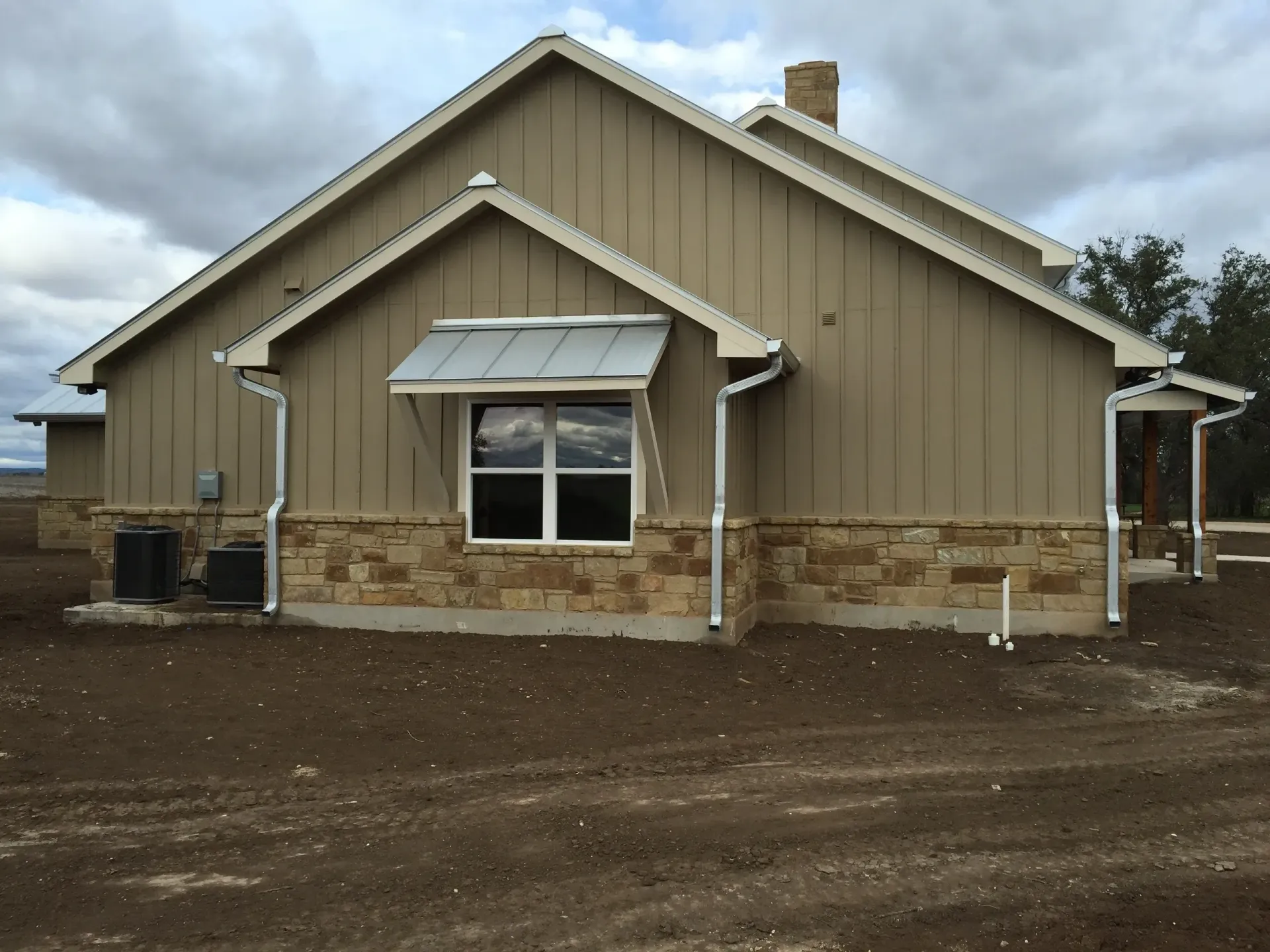 Kitchen with blue island, white countertops, brick backsplash, and hanging black pendant lights.