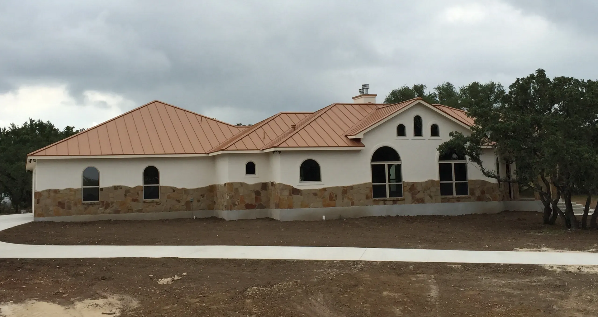 Empty room with brown glossy floor, white walls, black trim, chandelier, and a hallway.