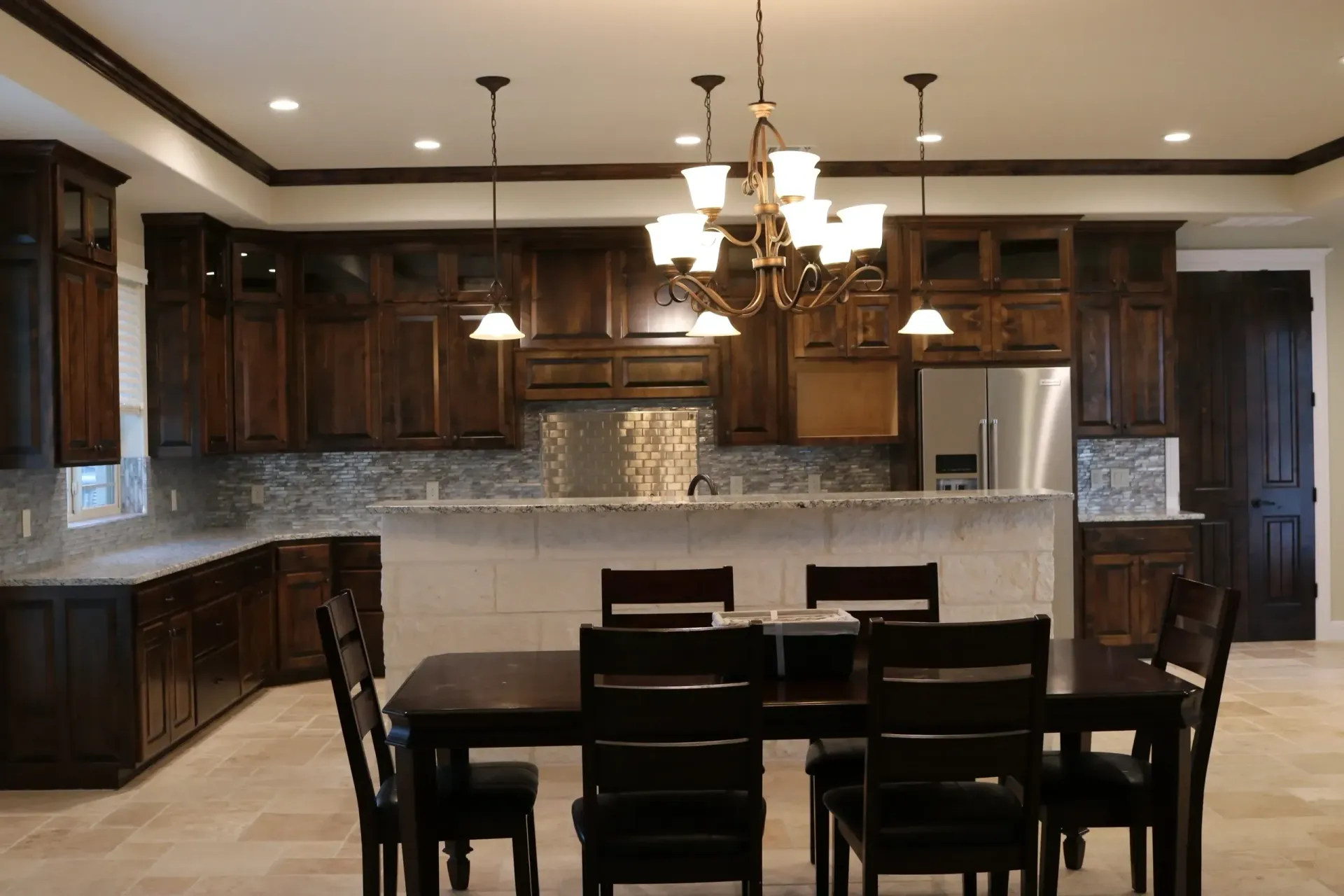 Kitchen with granite countertop island, dark cabinets, and bronze faucet.